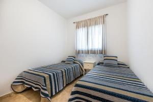 Dos camas en una habitación con paredes blancas y una ventana. en COMFORTABLE, CLOSE TO THE BEACH, POOL, NEW, PADDLE, en Rincón de la Victoria 48 fotos más