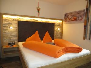 a bed with orange pillows on top of it at Apart Almrausch in Nauders