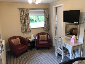 een hotelkamer met een bureau, stoelen en een televisie bij Calcutts House in Ironbridge