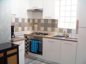 une cuisine avec des armoires blanches et un four à plaques de cuisson dans l'établissement Gîte, jacuzzi & vin au grenier de Madiran, à Madiran