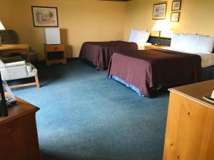 a hotel room with two beds and a chair at Don Q Inn in Dodgeville
