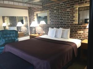a hotel room with a bed and a brick wall at Don Q Inn in Dodgeville