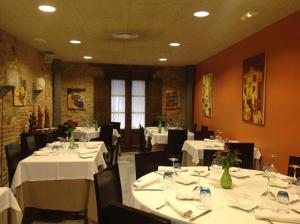 a dining room with white tables and black chairs at Hostal El Lechuguero in Cascante