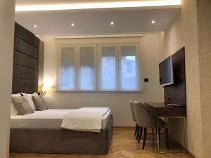 a bedroom with a bed and a desk and a television at Aria Royal apartment in Belgrade