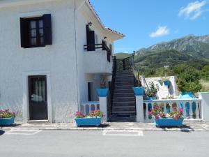 una casa blanca con macetas azules de flores delante de ella en Studios Popi en Kokkari