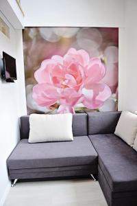 um sofá num quarto com uma pintura de uma flor rosa em Lofts - Kaunas airport em Karmėlava
