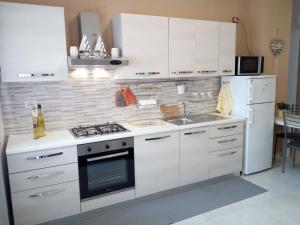 a kitchen with white cabinets and a stove and a sink at Mira in Pescara