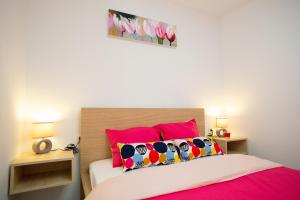 ein Schlafzimmer mit einem rosa und weißen Bett mit rosa Kissen in der Unterkunft Apartman Matej with pool Povljana in Povljana