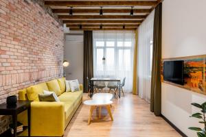 a living room with a yellow couch and a brick wall at RIS Dalma Collection Yerevan in Yerevan