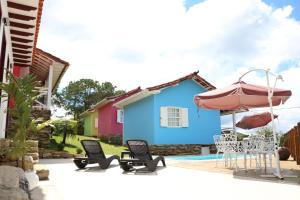 a patio with chairs and an umbrella and a house at Biz & Biu Pousada Lavras Novas in Lavras Novas