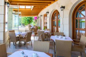 ein Restaurant mit Tischen, Stühlen und Fenstern in der Unterkunft Anita Beach Hotel- Adults Only in Rethymno