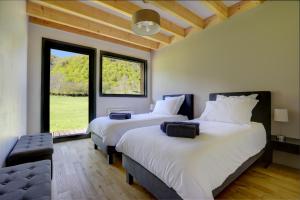 2 Betten in einem Zimmer mit einem großen Fenster in der Unterkunft La Dormeuse du Val in Chambon-sur-Lac