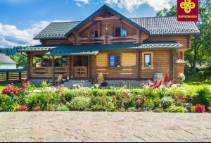 a log cabin with flowers in front of it at Карпатське Щастя in Verkhovyna