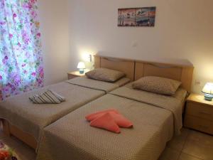 two beds in a hotel room with two red pillows at LARINΑKI'S STUDIO No1 in Amorgos