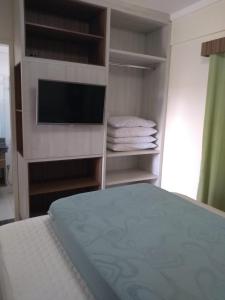 a bedroom with a bed and a tv and shelves at Apartamento Lacqua Di Roma in Caldas Novas