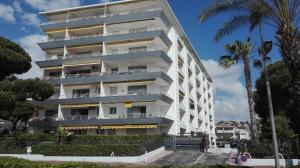 un edificio blanco con palmeras delante en Grand studio climatisé en bord de mer avec parking sécurisé, en Golfe-Juan