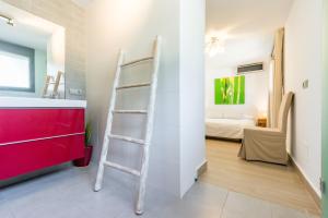 a bathroom with a ladder next to a sink and a bedroom at Nyumba ya Sun in Cala Tarida