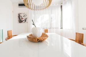 a white dining room with a wooden bowl on a white table at Nyumba ya Sun in Cala Tarida