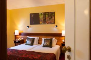 two beds in a hotel room with yellow walls at Aldeia da Fonte Hotel in Lajes do Pico