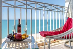 una mesa con un bol de frutas y copas de vino en el balcón en Apartment Magnolia Rustaveli 62 en Batumi