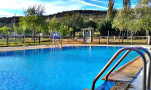 una piscina azul con parque infantil en Entrerrobles, en Valdeavellano de Tera