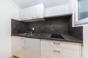 een keuken met witte kasten en een wastafel bij Apartments Gavran in Baška Voda