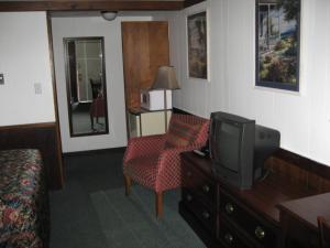 a hotel room with a tv and a chair at Sea Whale Motel in Middletown