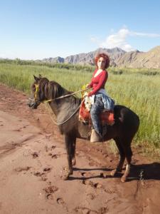 a young girl riding a horse on a dirt road at Hotel Hacienda Casa Blanca in Tinogasta