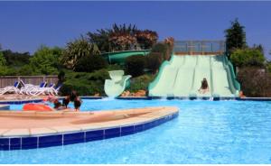 uno scivolo d'acqua in una piscina con due persone sopra di Mobil-Home 4p Privé Camping 5 étoiles Erdeven 7saints a Erdeven