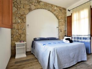 - une chambre avec un lit et un mur en pierre dans l'établissement Villa Menhir, à Lotzorai