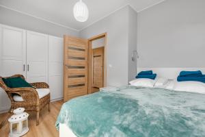 ein weißes Schlafzimmer mit einem großen Bett und einem Stuhl in der Unterkunft Apartament Konik Morski - Apartamenty Vento in Władysławowo