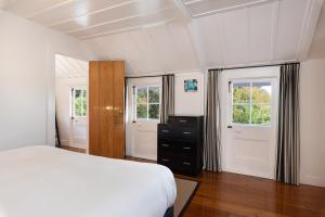 
a bedroom with a bed and a dresser at The Old Oak Boutique Hotel in Mangonui
