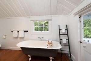 
a white bath tub sitting next to a window at The Old Oak Boutique Hotel in Mangonui
