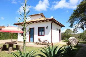 una pequeña casa blanca con mesa y sombrilla en Chalé Clássico, en Lavras Novas