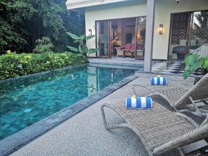 a swimming pool with two chairs next to a house at Villa with private pool at Villa Nirvana Ubud in Ubud