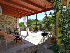 eine Terrasse mit einem Tisch, Stühlen und einem Grill in der Unterkunft Stavies Traditional Stone House in Stáviai