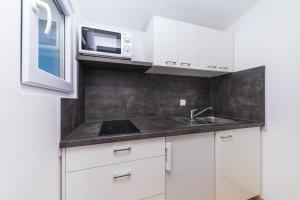 a kitchen with white cabinets and a sink and a microwave at Apartments Gavran in Baška Voda