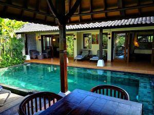 a swimming pool with a table and chairs next to a house at Villa with private pool at Villa Nirvana Ubud in Ubud