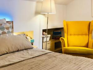 1 dormitorio con 1 cama y 1 silla amarilla en Ático Centro Málaga, en Málaga