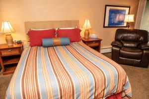 a bedroom with a large bed and a leather chair at 111 Vail International Condo in Vail