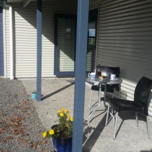 uma mesa e cadeiras sentadas ao lado de um edifício em Waihakeke Cottage em Carterton
