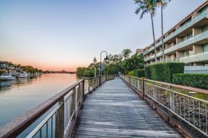 una pasarela de madera sobre un río junto a un edificio en Hotel Laguna, en Noosa Heads