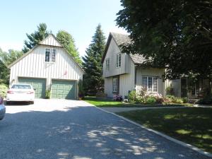 a white house with a car parked in a driveway at Cedar Gables Bed & Breakfast in Niagara-on-the-Lake