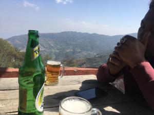 a woman sitting at a table with a bottle of beer at Hotel Galaxy View Tower in Nagarkot