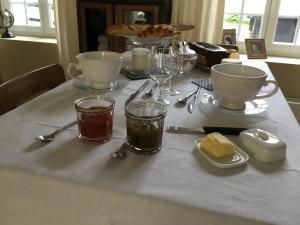 uma mesa com uma toalha de mesa branca com óculos e colheres em La Parenthese em Montreuil-sur-Mer