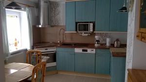 a kitchen with blue cabinets and a table and a microwave at Ferienwohnung Ahoi in Putbus