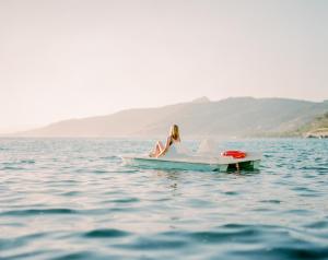 a woman sitting on a boat in the water at Blue Bay in Cefalù