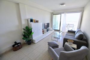 een woonkamer met een bank en stoelen en een tv bij Tierra de mar 67 in Denia