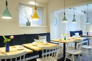 una sala da pranzo con tavoli in legno e sedie bianche di Hotel am Südwäldchen a Westerland