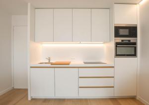 a white kitchen with white cabinets and a sink at Studio Zeezicht fully renovated in Ostend